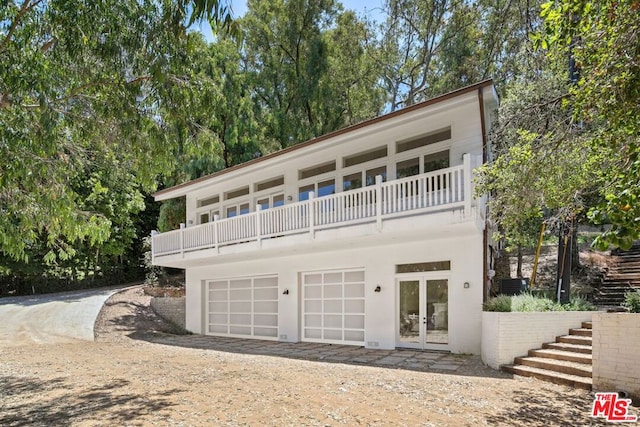 view of property featuring a garage, a balcony, and french doors