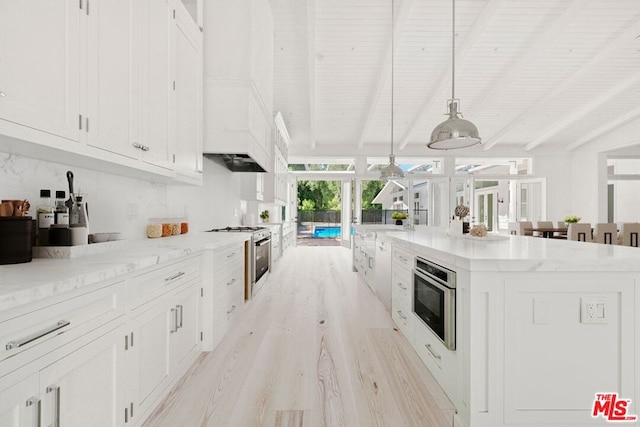 kitchen featuring white cabinets, hanging light fixtures, light hardwood / wood-style flooring, beamed ceiling, and a large island