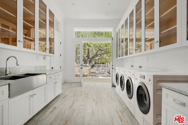 laundry area featuring cabinets, light hardwood / wood-style floors, washing machine and dryer, and sink