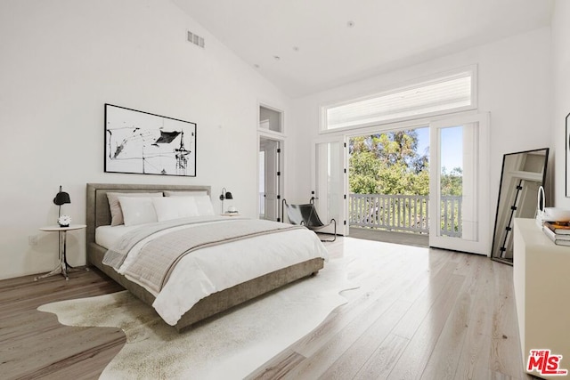 bedroom with access to outside, high vaulted ceiling, and light wood-type flooring