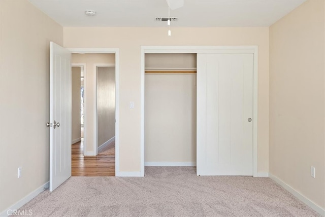 unfurnished bedroom featuring light colored carpet and a closet