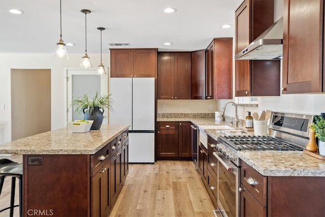 kitchen with a breakfast bar area, stainless steel range, a center island, light wood-type flooring, and white refrigerator