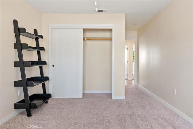 unfurnished bedroom featuring a closet and light carpet