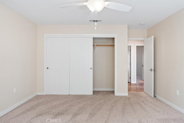 unfurnished bedroom with a closet, light colored carpet, and ceiling fan