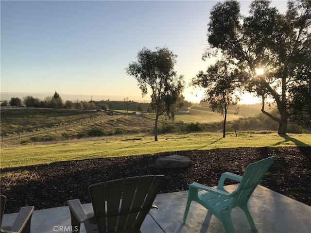 yard at dusk with a patio area and a rural view