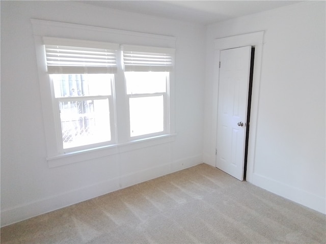 unfurnished room featuring light colored carpet and plenty of natural light