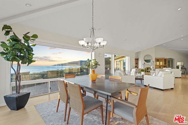 dining space featuring lofted ceiling with beams, a water view, a notable chandelier, and light hardwood / wood-style flooring