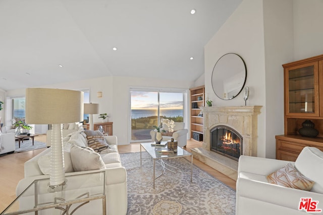 living room with a premium fireplace, lofted ceiling, and light wood-type flooring