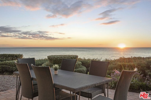 patio terrace at dusk featuring a water view