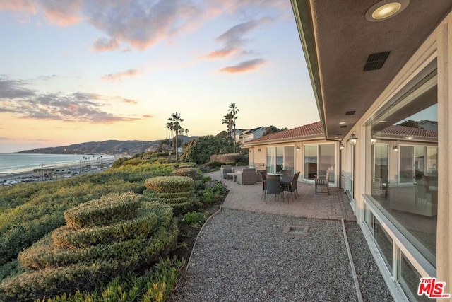 yard at dusk featuring a patio area and a water and mountain view