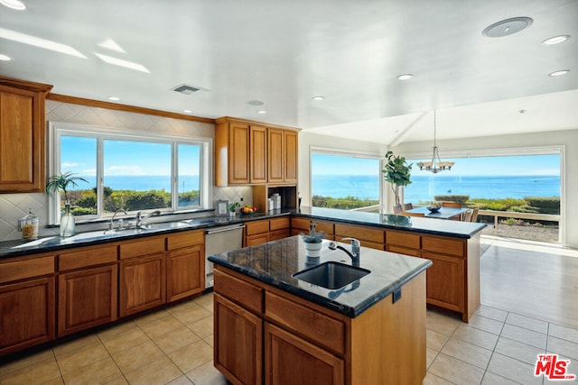 kitchen with sink, decorative light fixtures, a center island with sink, stainless steel dishwasher, and kitchen peninsula