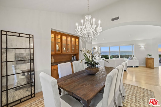 dining room with lofted ceiling, a notable chandelier, and light wood-type flooring