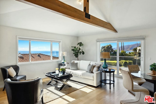 living room with a water view, lofted ceiling with beams, and light wood-type flooring