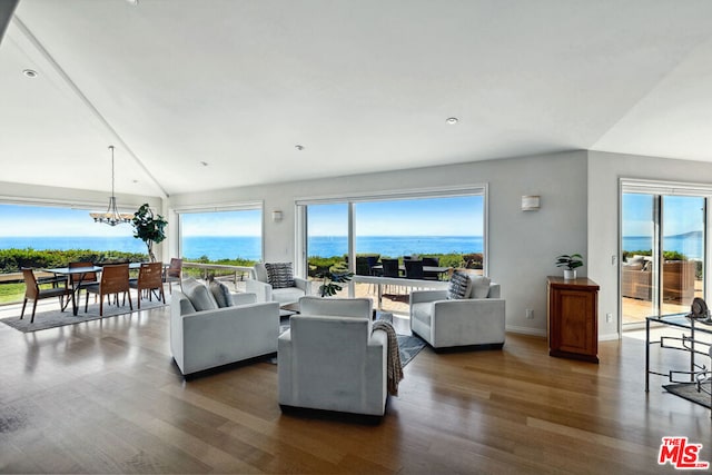 living room featuring vaulted ceiling, a water view, dark wood-type flooring, and a chandelier