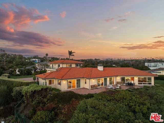 back house at dusk with a patio