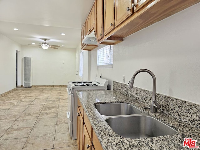 kitchen with stainless steel range with gas cooktop, sink, ceiling fan, light tile patterned floors, and stone countertops