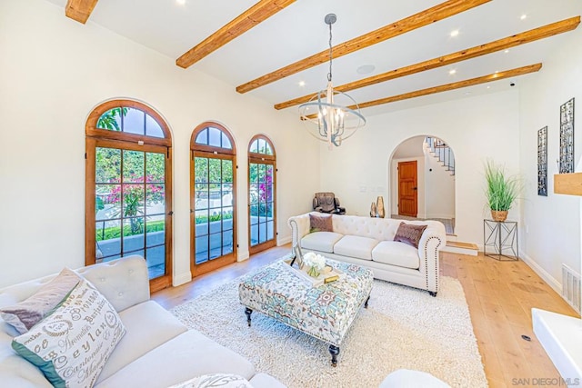 living room featuring beam ceiling, light wood-type flooring, and an inviting chandelier