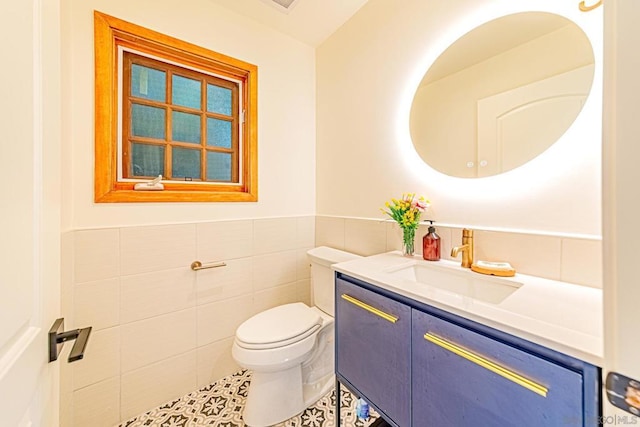 bathroom featuring tile patterned flooring, vanity, toilet, and tile walls