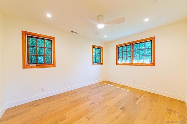 empty room featuring ceiling fan, plenty of natural light, and light hardwood / wood-style floors