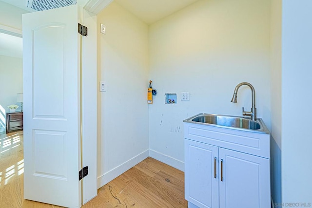 clothes washing area with cabinets, washer hookup, light hardwood / wood-style floors, and sink