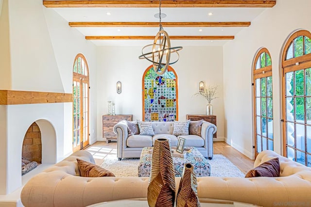 living room with beamed ceiling, french doors, light hardwood / wood-style floors, and a chandelier