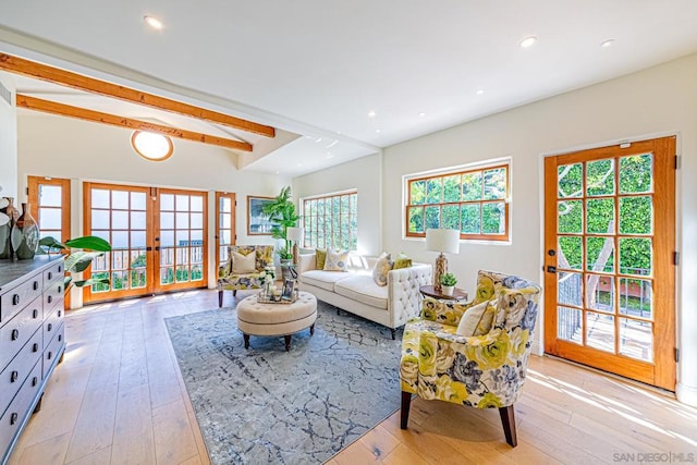 living room featuring french doors, light wood-type flooring, a wealth of natural light, and beam ceiling