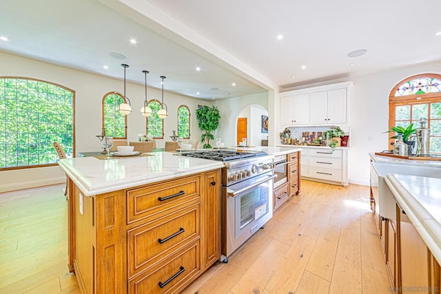 kitchen featuring high end stove, a wealth of natural light, white cabinets, and a kitchen island