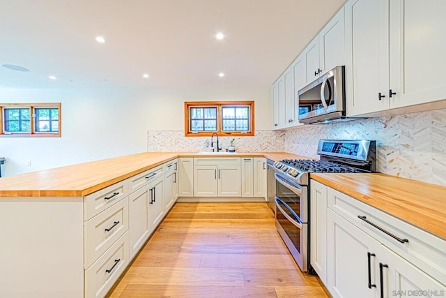 kitchen featuring wooden counters, sink, light hardwood / wood-style floors, white cabinetry, and stainless steel appliances