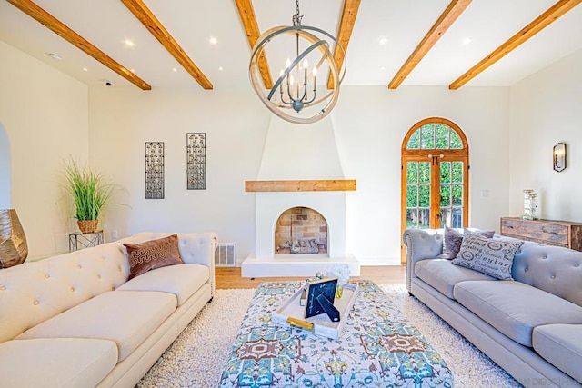 living room featuring a large fireplace, light hardwood / wood-style flooring, an inviting chandelier, beamed ceiling, and a high ceiling