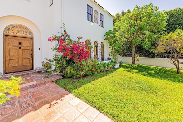 view of exterior entry featuring a lawn