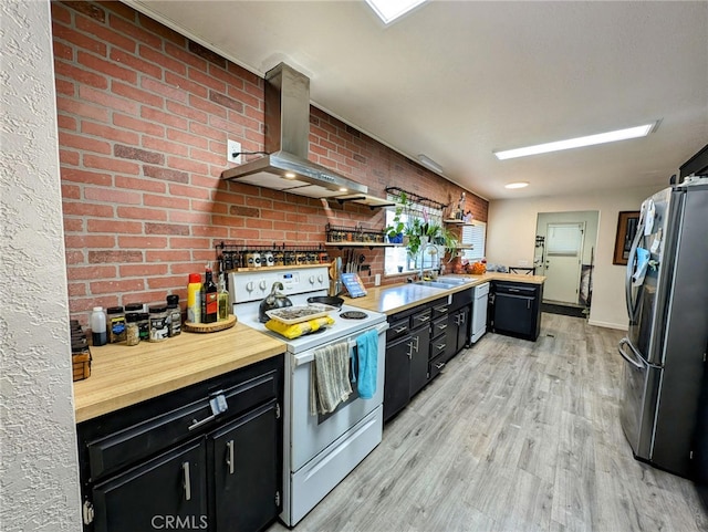 kitchen with light wood-type flooring, sink, wall chimney range hood, white appliances, and brick wall