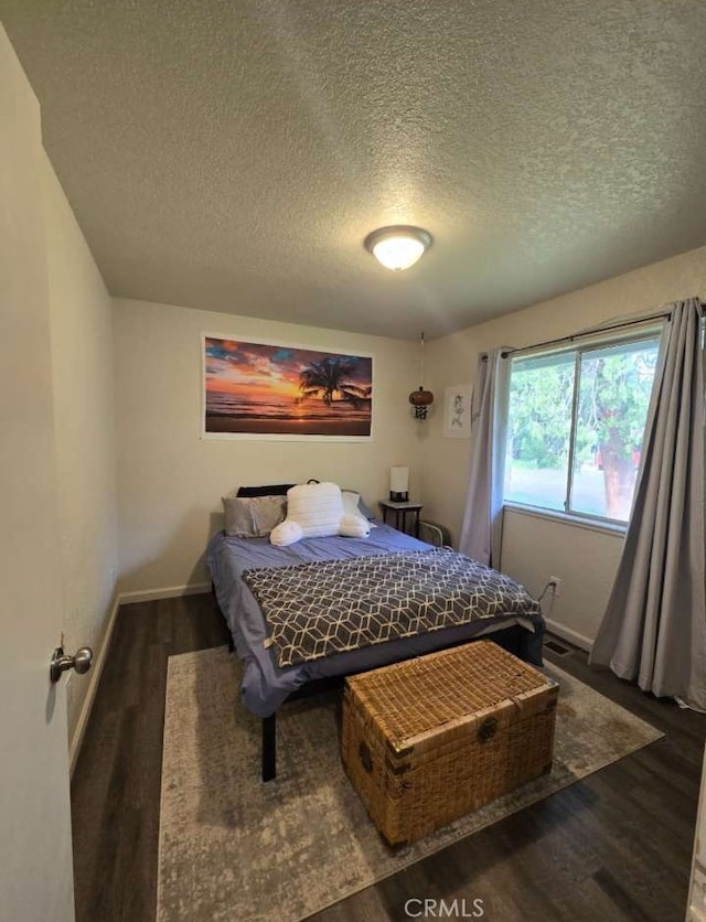 bedroom with a textured ceiling and dark wood-type flooring