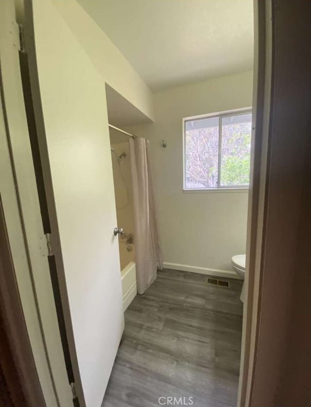 bathroom featuring wood-type flooring, shower / tub combo, and toilet