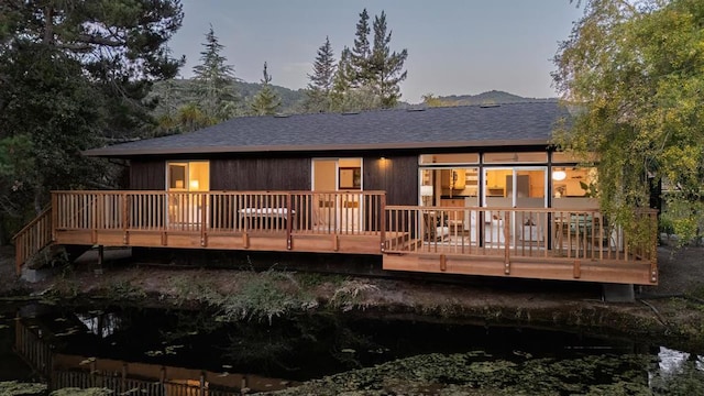 back house at dusk featuring a deck