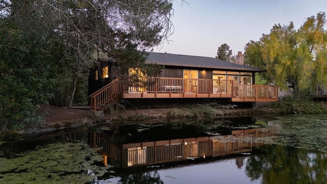 back house at dusk featuring a deck with water view