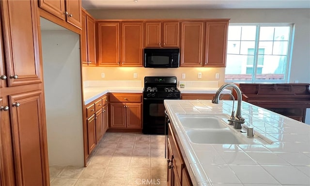 kitchen featuring tile countertops, sink, and black appliances