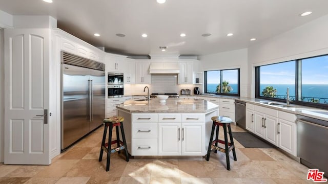 kitchen featuring sink, a kitchen island with sink, a breakfast bar area, stainless steel appliances, and a water view