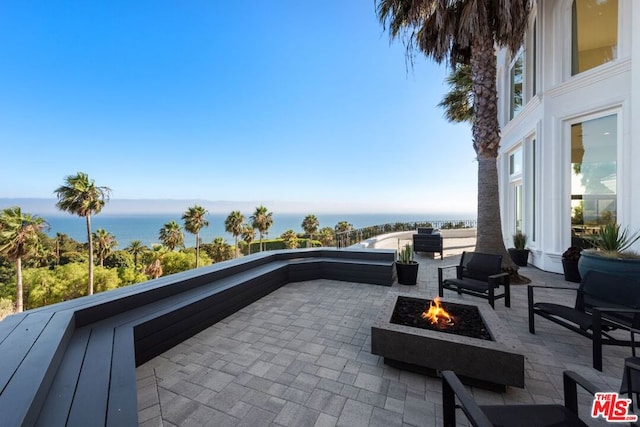 view of patio / terrace featuring a balcony, a fire pit, and a water view