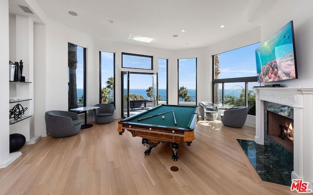 game room with billiards, light wood-type flooring, and a fireplace