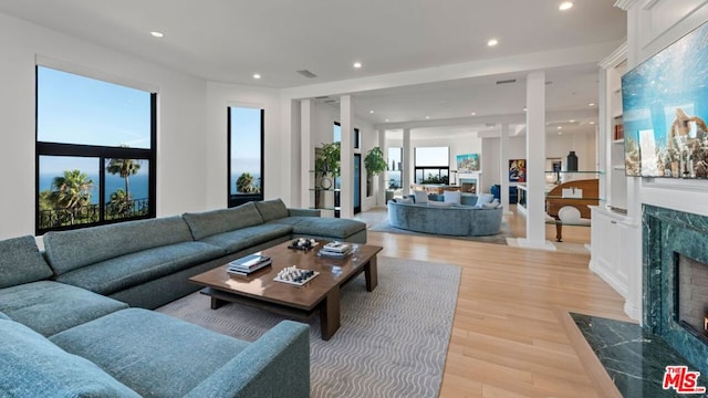 living room with a high end fireplace and light hardwood / wood-style flooring