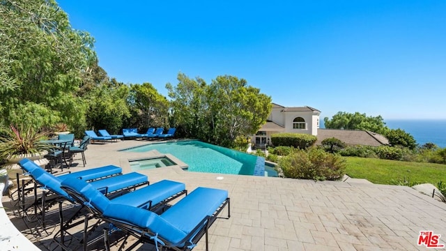 view of pool featuring a patio area, a water view, and an in ground hot tub