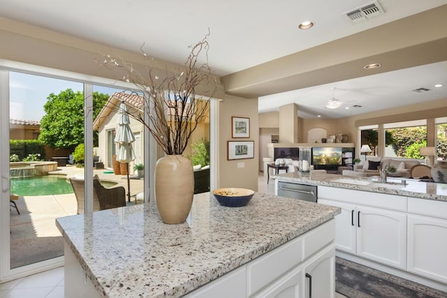 kitchen featuring dishwasher, sink, light stone countertops, light tile patterned floors, and white cabinetry