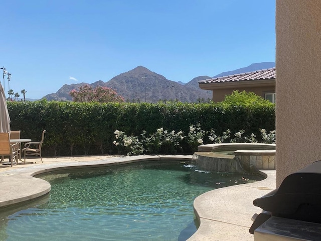 view of swimming pool featuring an in ground hot tub, a mountain view, and a patio