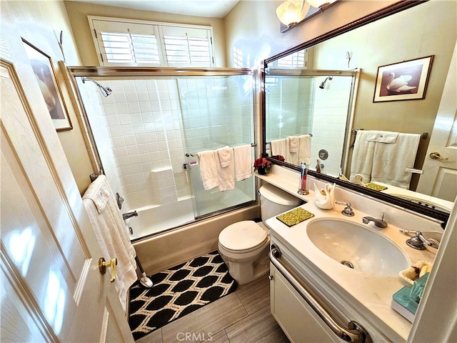 full bathroom featuring enclosed tub / shower combo, vanity, and toilet