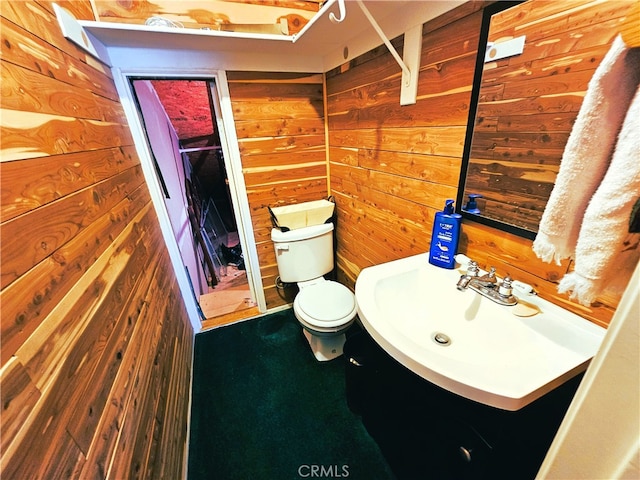 bathroom featuring vanity, wood walls, and toilet