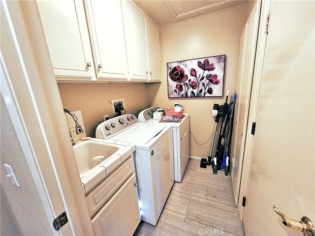 laundry area with light hardwood / wood-style flooring, washing machine and clothes dryer, and cabinets