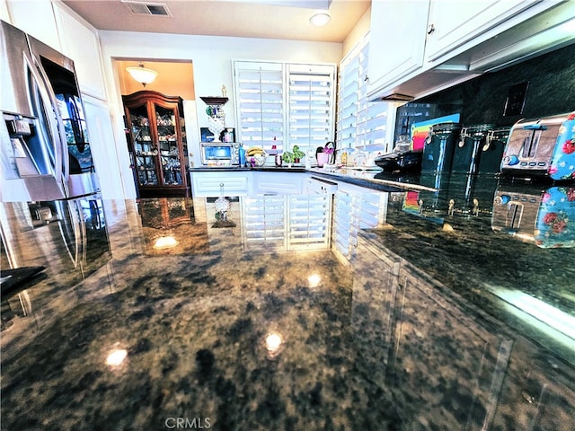 kitchen featuring dark stone counters and white cabinetry