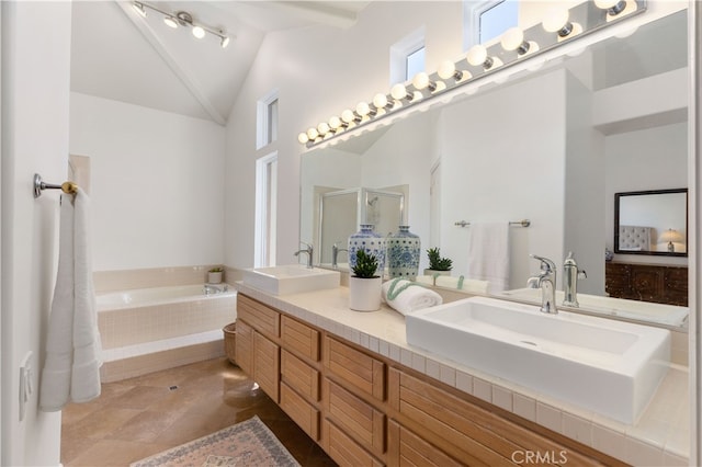 bathroom with tile patterned floors, vanity, vaulted ceiling, and tiled tub