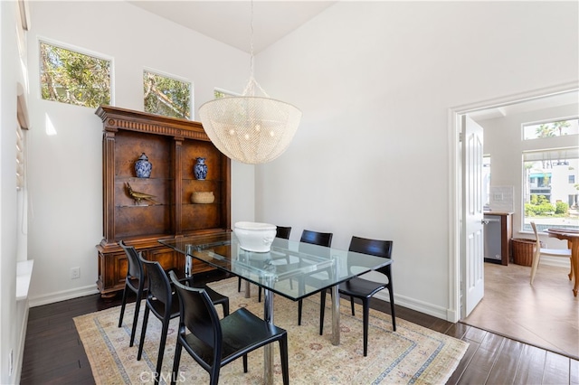 dining space with a towering ceiling and dark hardwood / wood-style flooring