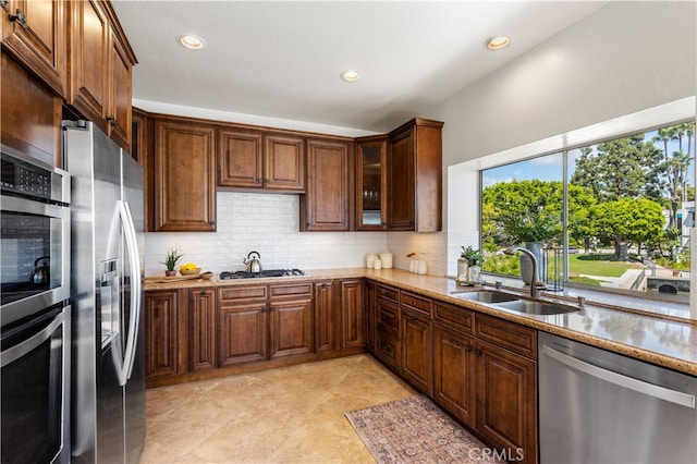 kitchen with tasteful backsplash, light stone counters, stainless steel appliances, sink, and light tile patterned flooring